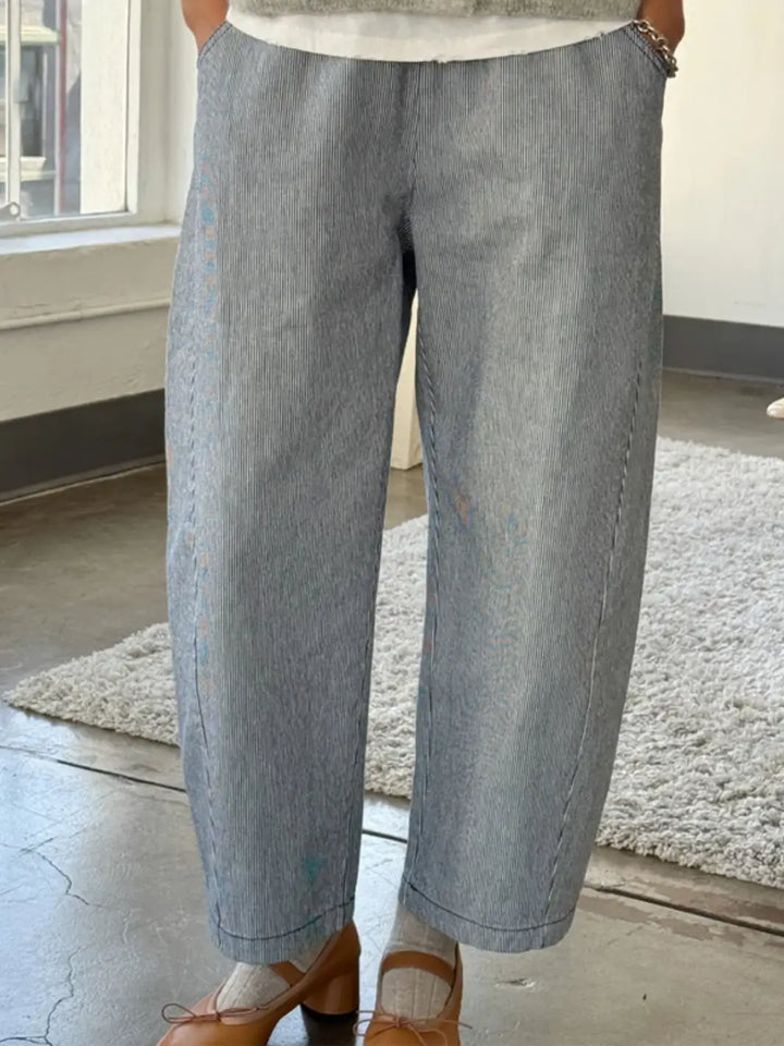 A person stands indoors wearing the wide-leg Le Bon Shoppe Arc Pants - Blue Stripe paired with brown heeled Mary Jane shoes | Twentyseven Toronto