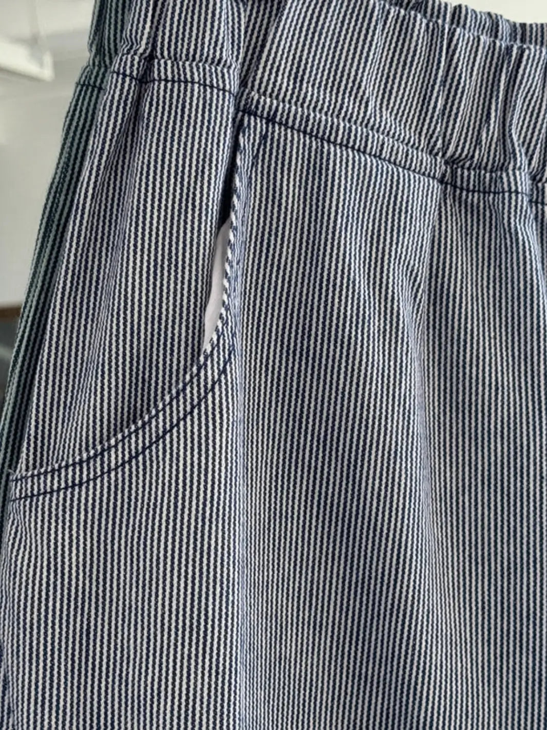 A close-up shot focuses on the elastic waistband, side pocket, and fine pinstripe fabric detail of the Le Bon Shoppe Arc Pants - Blue Stripe | Twentyseven Toronto