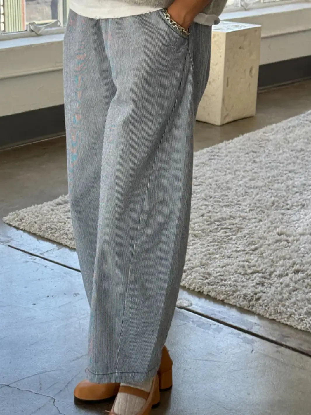 A side-profile view shows a person modeling the curved silhouette and relaxed fit of the Le Bon Shoppe Arc Pants - Blue Stripe in an indoor setting | Twentyseven Toronto