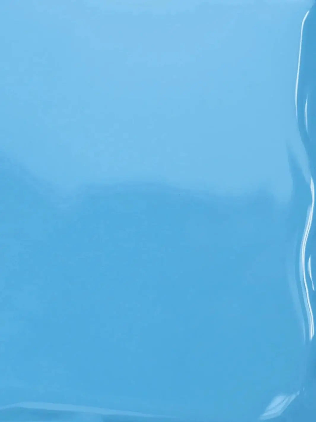 A close-up texture shot showing the smooth, glossy, liquid surface of the sky-blue BKIND Nail Polish in Blue Lagoon formula | Twentyseven Toronto
