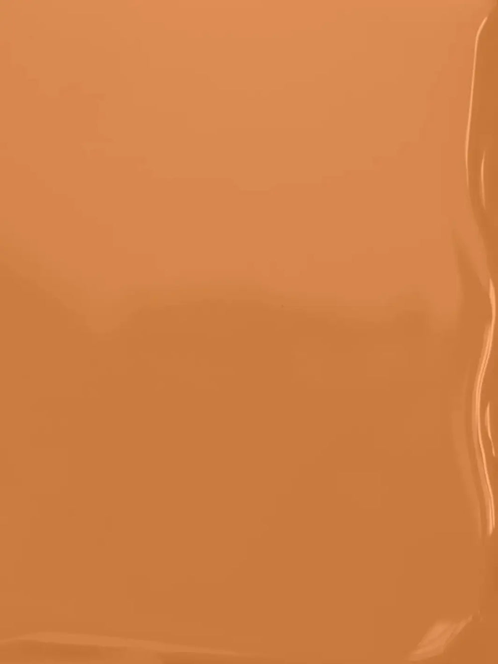A full-frame texture shot showing the smooth, glossy, liquid surface of the warm caramel-brown BKIND Nail Polish in Val-d'Or formula | Twentyseven Toronto