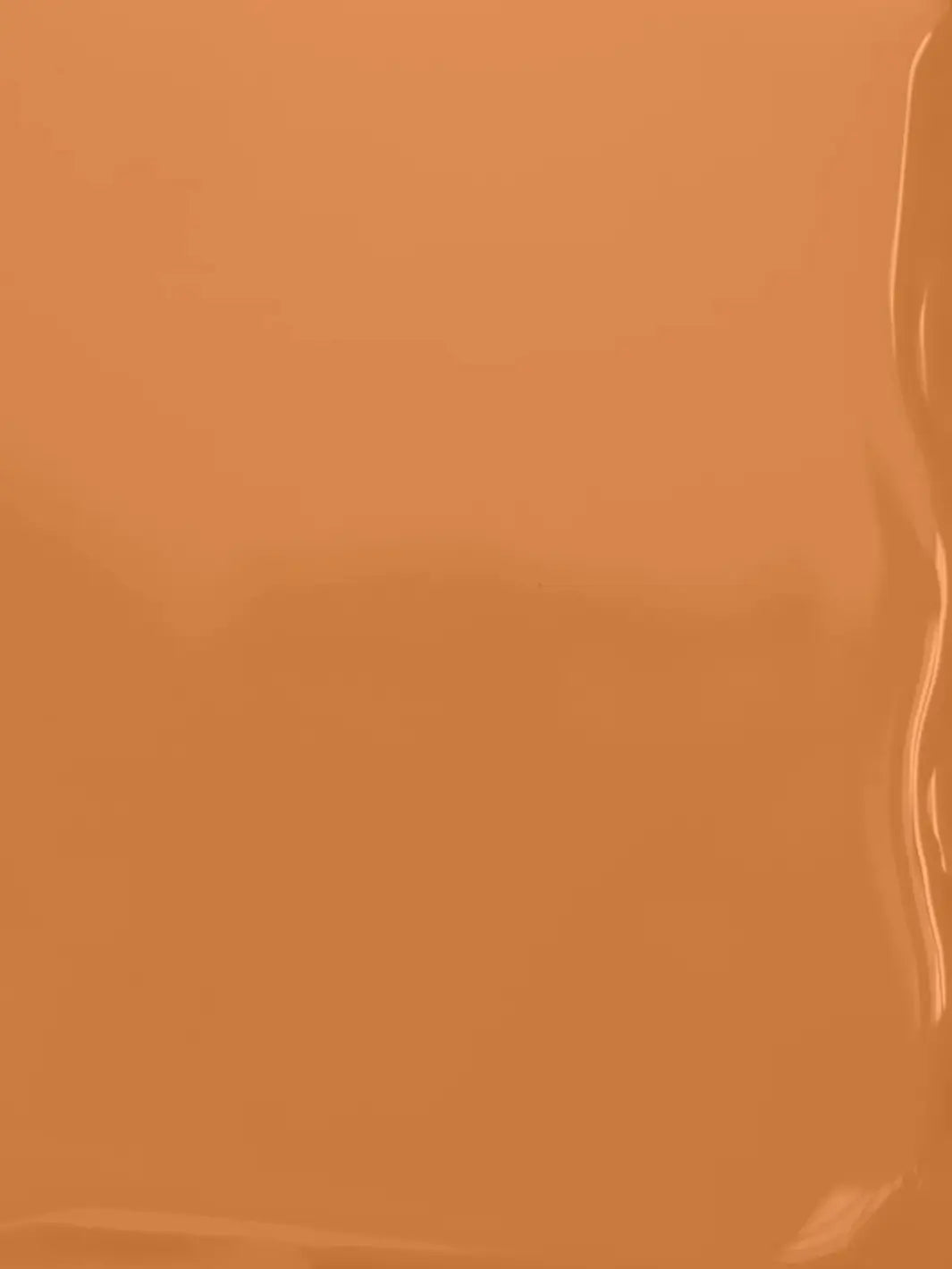 A full-frame texture shot showing the smooth, glossy, liquid surface of the warm caramel-brown BKIND Nail Polish in Val-d'Or formula | Twentyseven Toronto