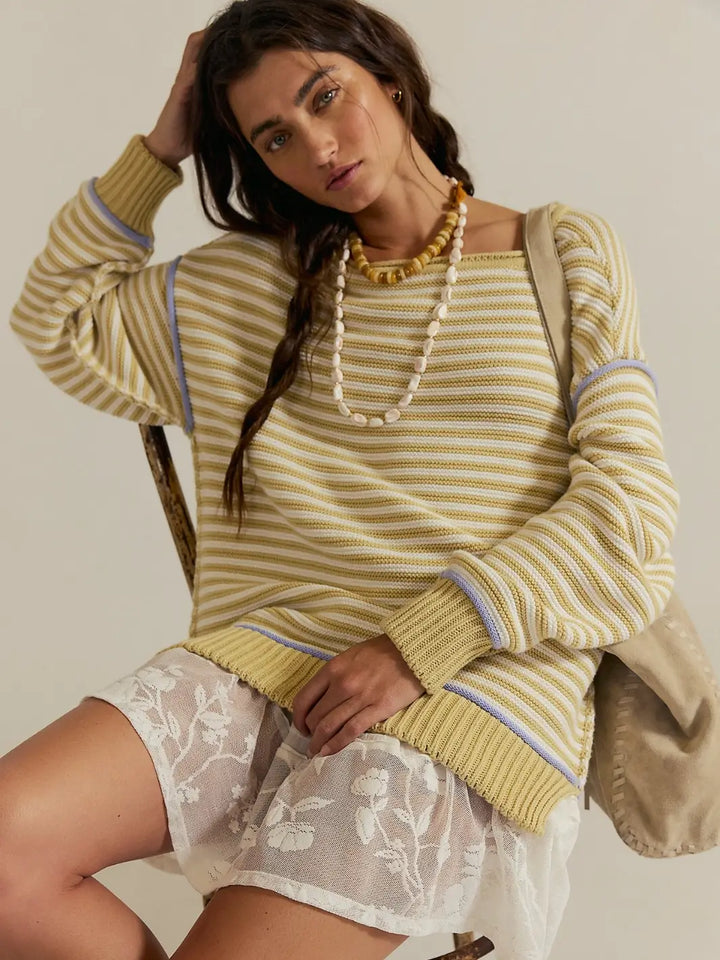 A model wearing the oversized, horizontally striped Free People We the Free Asher Pullover in Sand Combo styled with a white lace skirt and beaded necklaces | Twentyseven Toronto