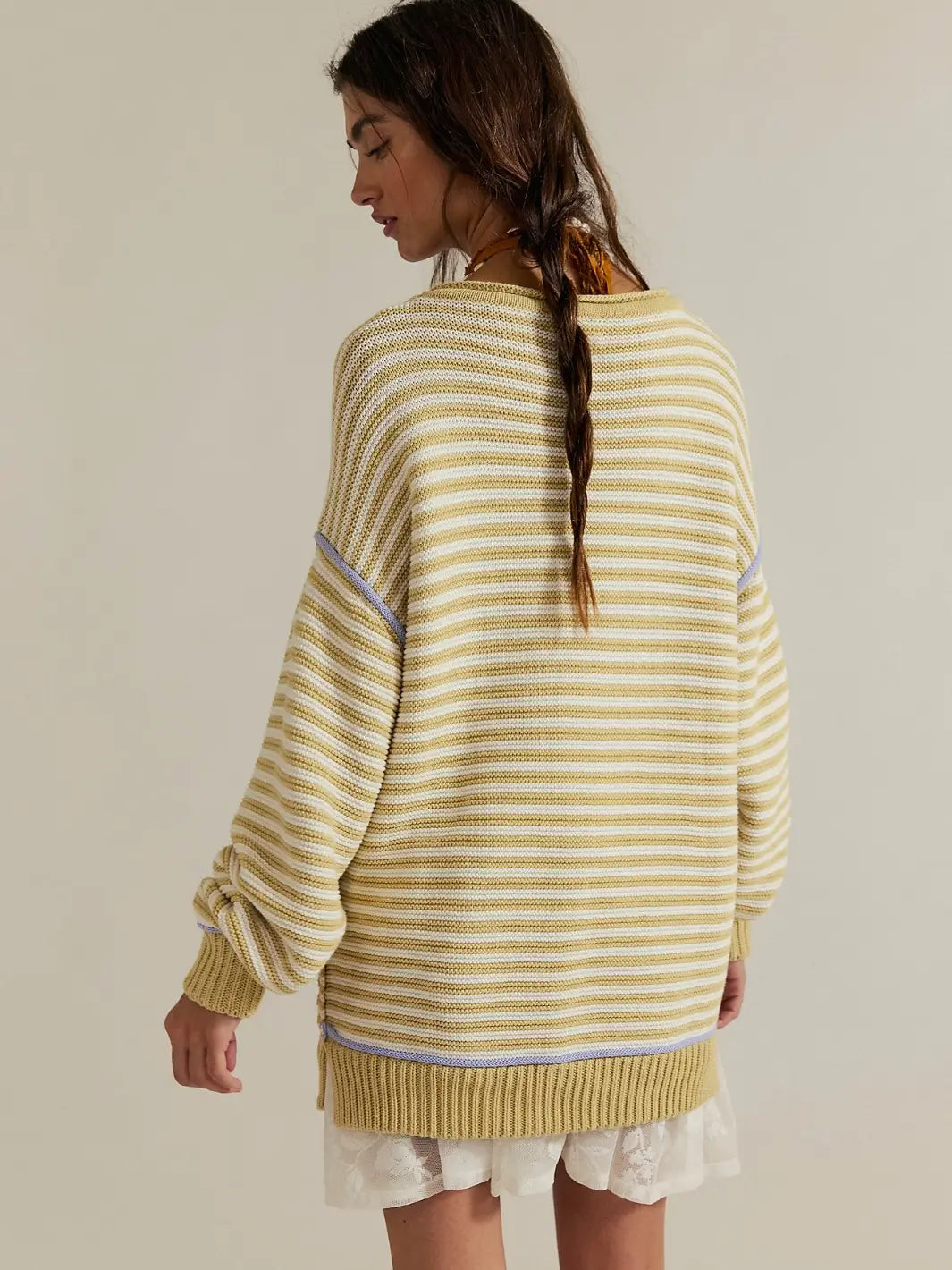 A rear view of a model wearing the relaxed silhouette, dropped shoulders, and subtle lavender trim detailing of the Free People We the Free Asher Pullover in Sand Combo | Twentyseven Toronto