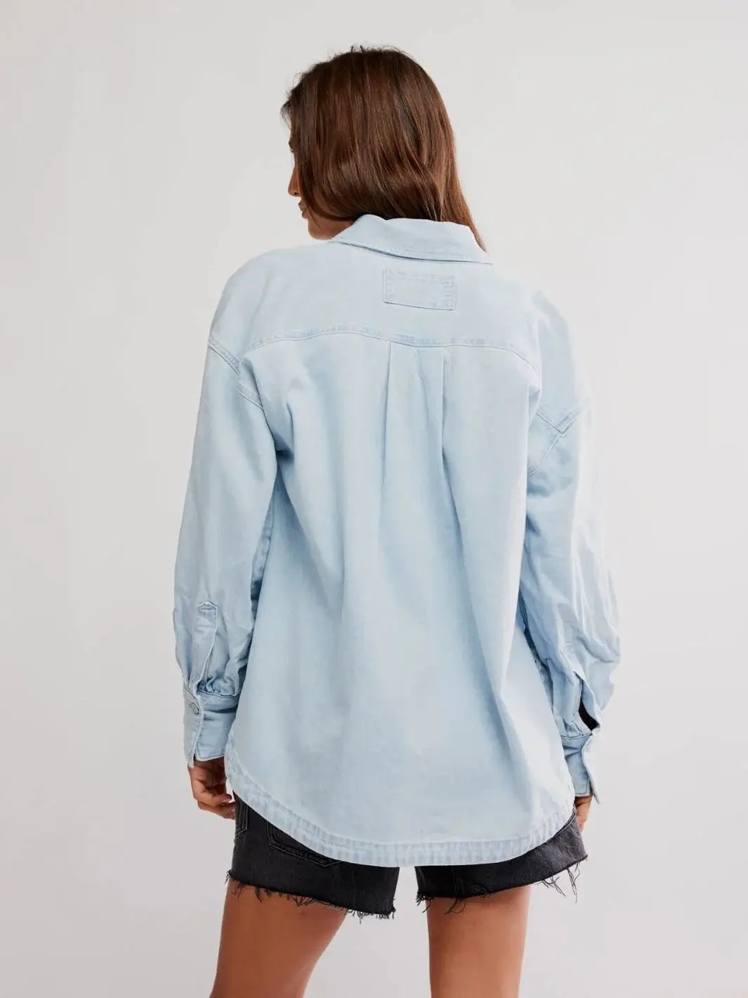 A rear view showcases the back yoke, central box pleat, and relaxed tailoring of the Free People Ashley Denim Shirt - Classic Blue Wash | Twentyseven Toronto