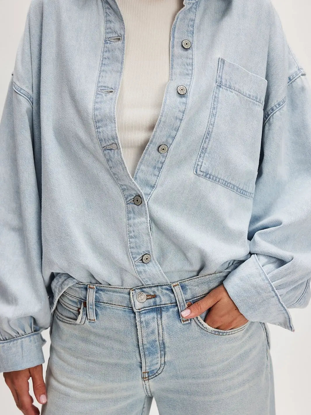 A detailed close-up shows the textured metal buttons and slouchy, tucked-in style of the Free People Ashley Denim Shirt - Classic Blue Wash | Twentyseven Toronto