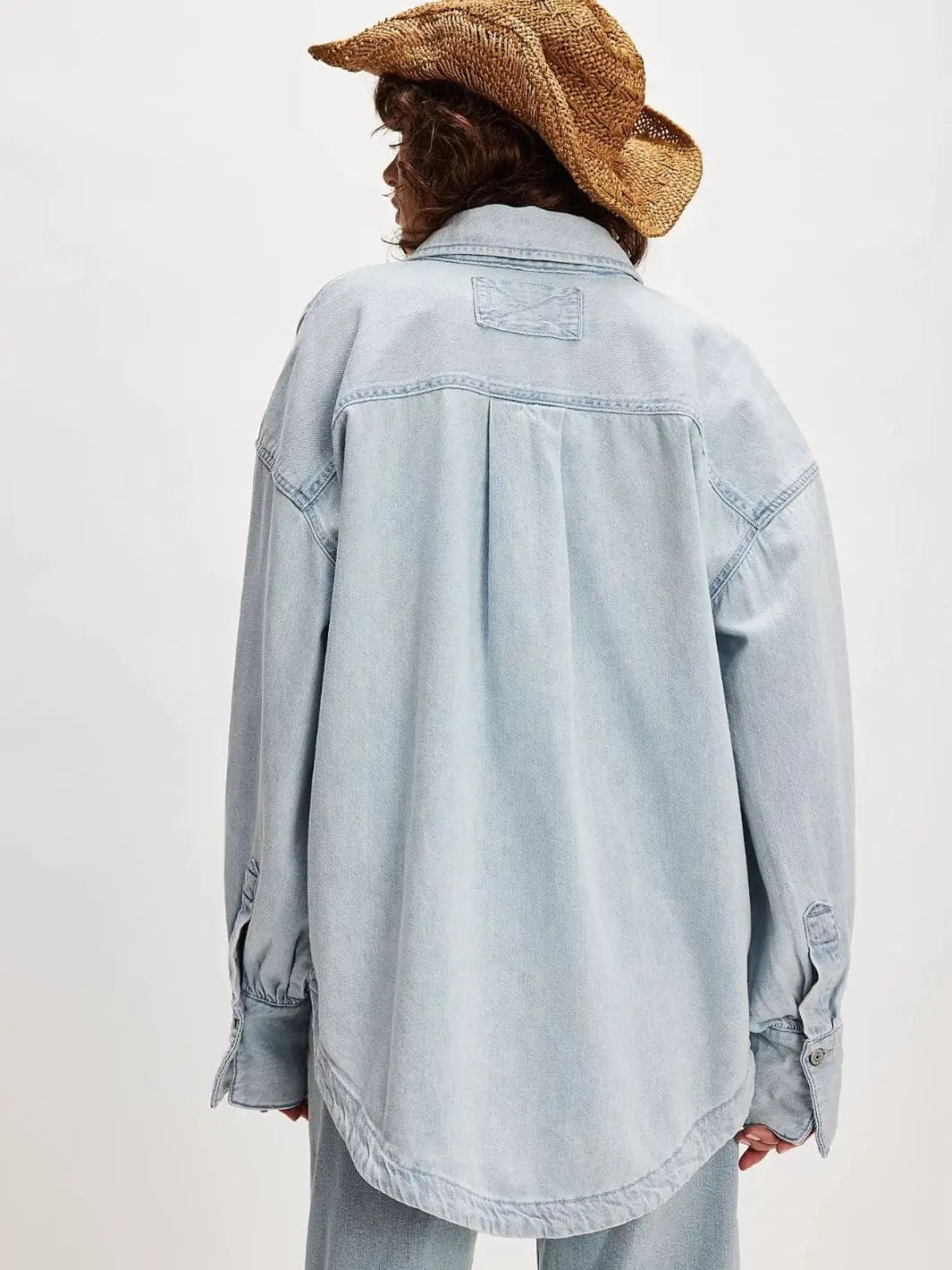 A view from behind highlights the clean back panel stitching, relaxed shoulders, and oversized silhouette of the Free People Ashley Denim Shirt - Classic Blue Wash | Twentyseven Toronto