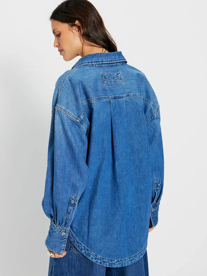 Woman wearing a blue denim shirt from Free People We the Free 'Ashley Denim Shirt' in 'Medium Wash' on a white background, back view | Twentyseven Toronto