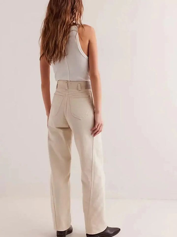A view from behind shows a model wearing the high-waisted Free People Aster Straight-Leg Jeans - Cream featuring a relaxed straight-leg fit and pointed back pockets styled with dark boots | Twentyseven Toronto