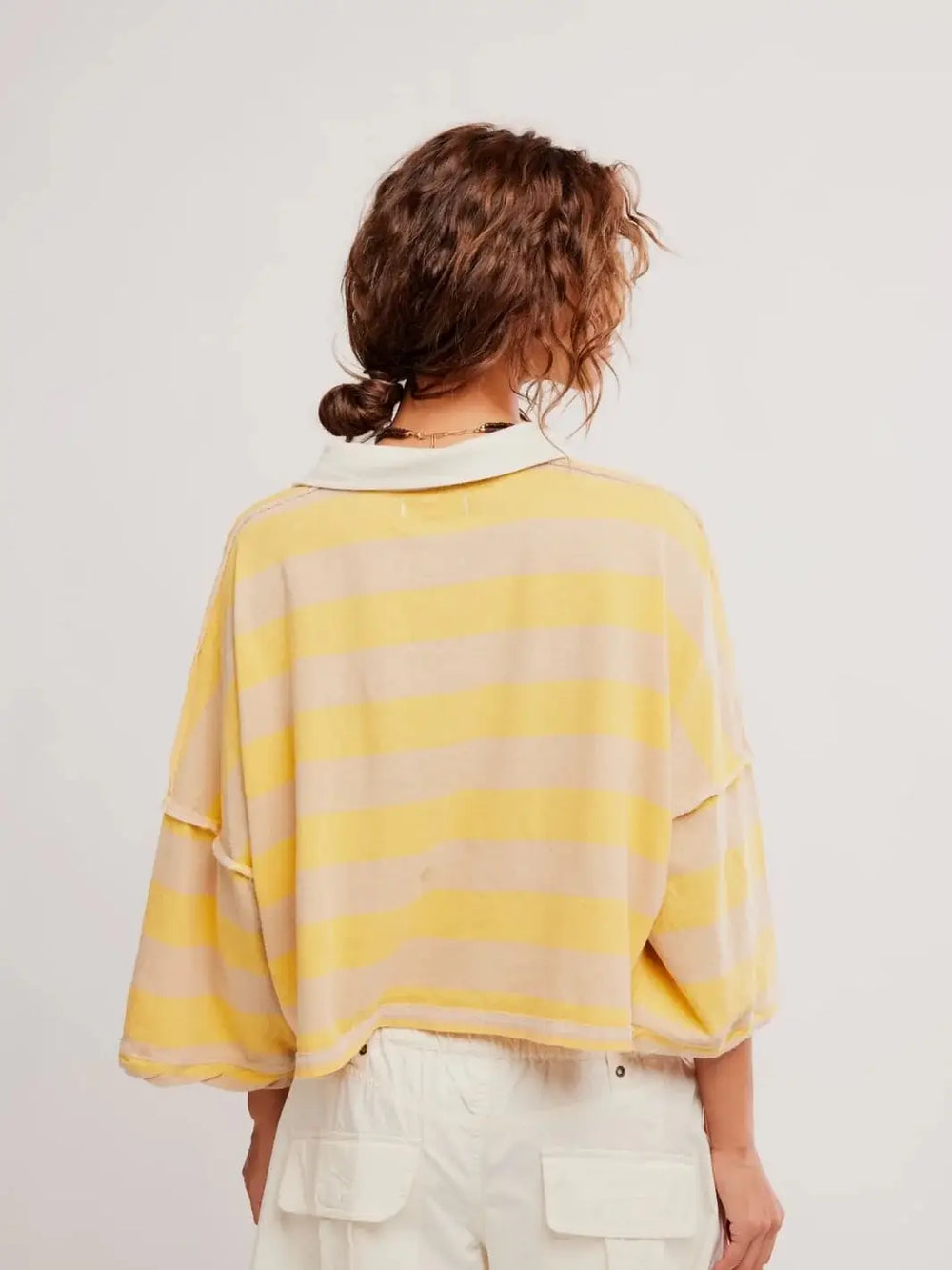 A rear view focuses on the slouchy, oversized drape and raw-edge seam detailing across the back of the Free People Auggie Tee in Oat Latte/Yellow Fin | Twentyseven Toronto