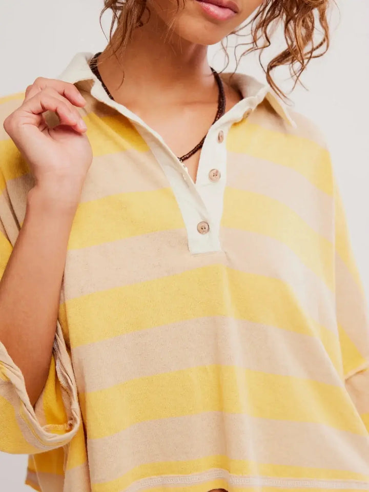 A close-up shot emphasizes the textured waffle-knit fabric, three-button placket, and contrasting collar of the Free People Auggie Tee in Oat Latte/Yellow Fin | Twentyseven Toronto