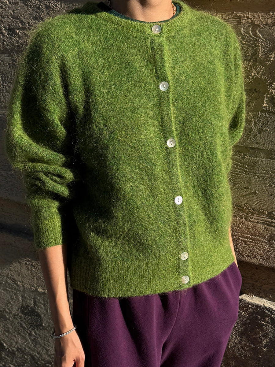 Model wearing the Le Bon Shoppe Ayla Cardigan in Artichoke with purple trousers, showcasing its relaxed fit, button-front closure and textured green knit | Twentyseven Toronto
