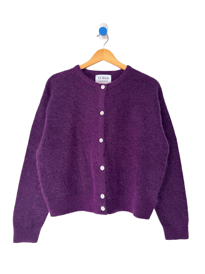 Le Bon Shoppe Ayla Mohair Cardigan in purple displayed on a wooden hanger, featuring a crew neckline and shell button front | Twentyseven Toronto