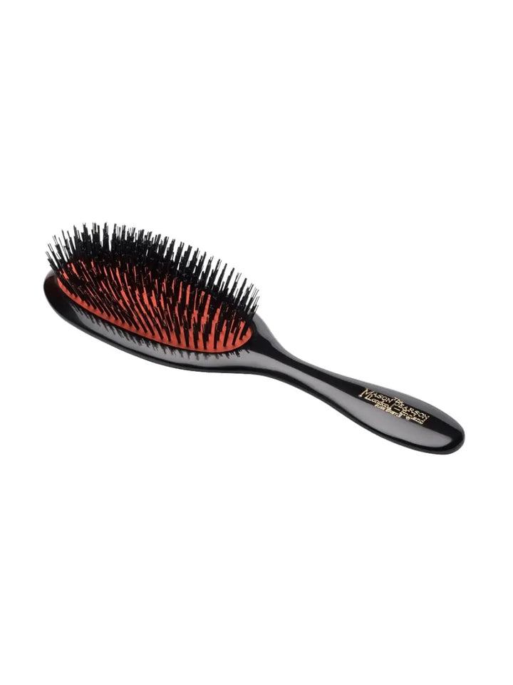A medium-sized black dressing hairbrush with a dark red cushion base is shown at an angle to display the profile of the Mason Pearson Handy All Boar Bristle Hairbrush B3 | Twentyseven Toronto