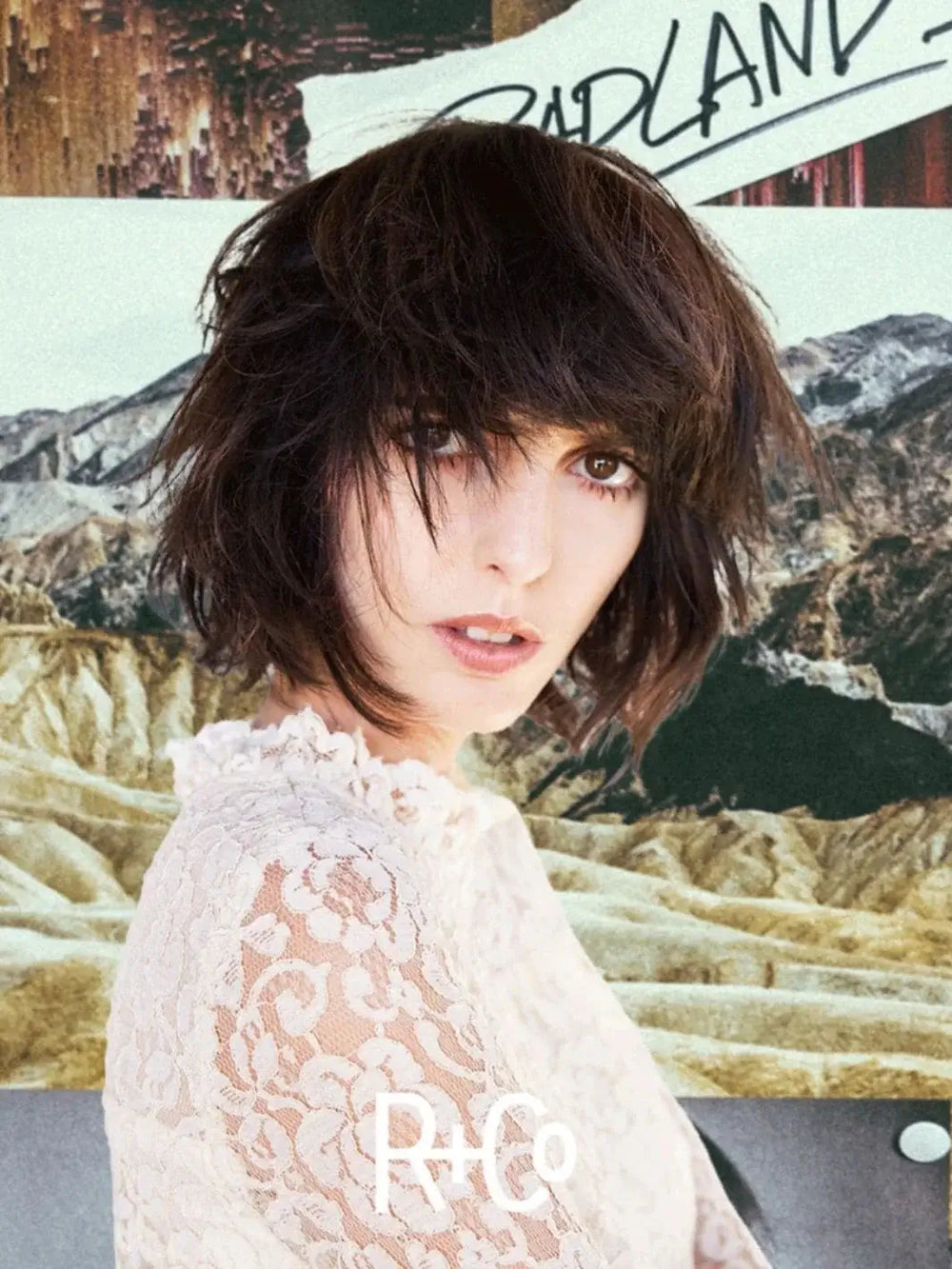 A model with a piecey, textured brunette haircut poses in front of a desert canyon backdrop that reflects the style of R+Co BADLANDS Dry Shampoo Paste | Twentyseven Toronto