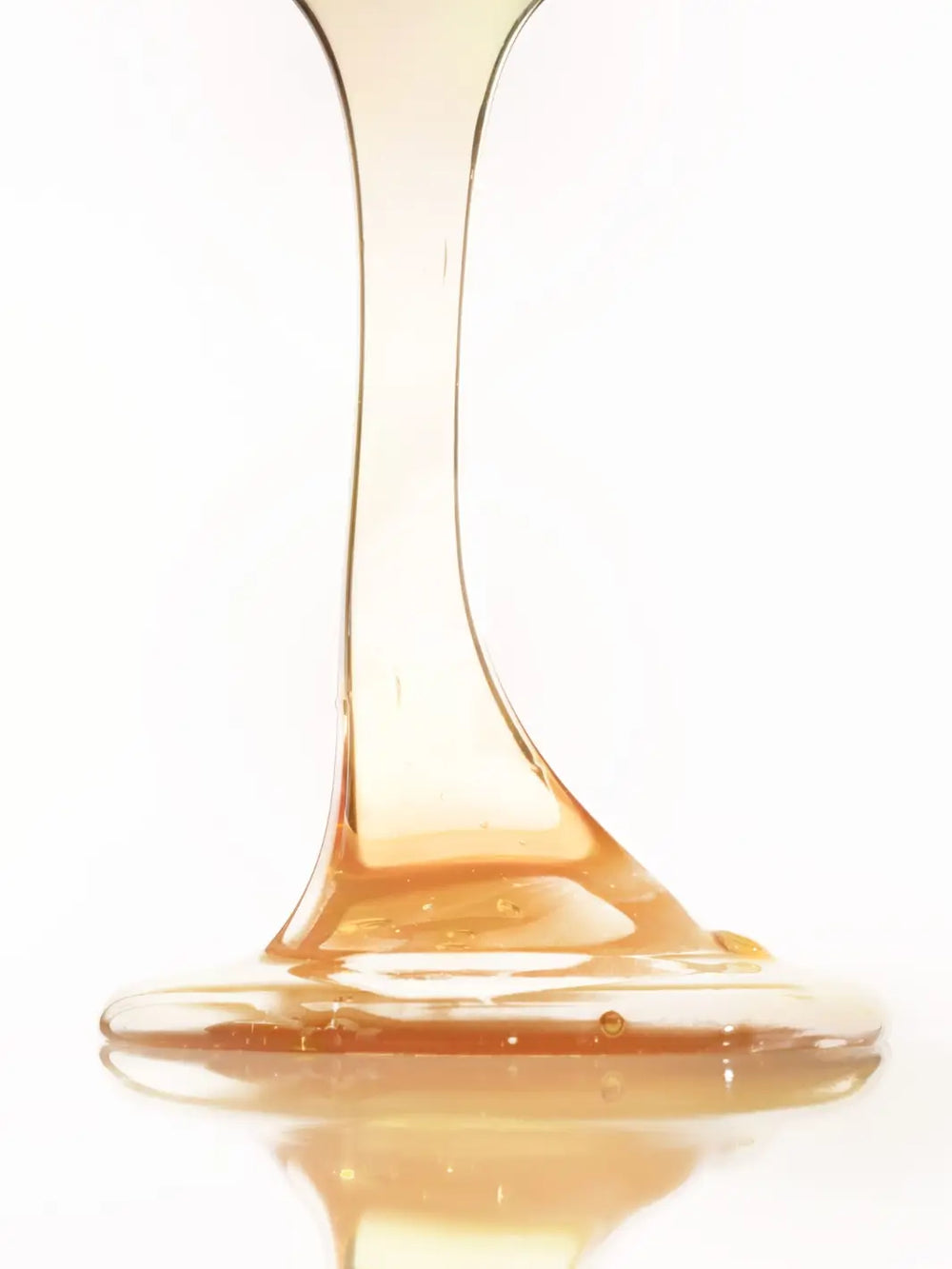 Close-up of gold 'Bain Traitant à la Propolis' shampoo liquid texture on a white background | Twentyseven Toronto