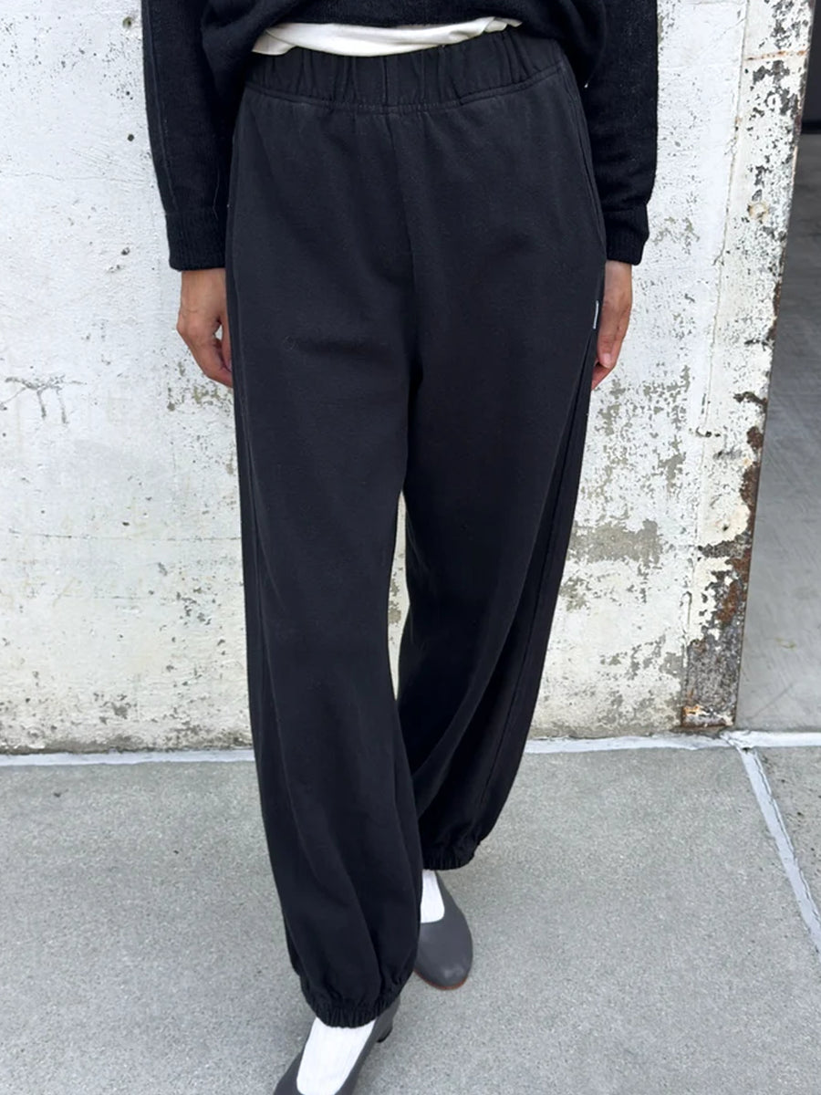 Front view of black Balloon Pants featuring an elastic waistband, loose tapered legs and gathered ankle cuffs, styled with a black sweater and grey heels | Twentyseven Toronto