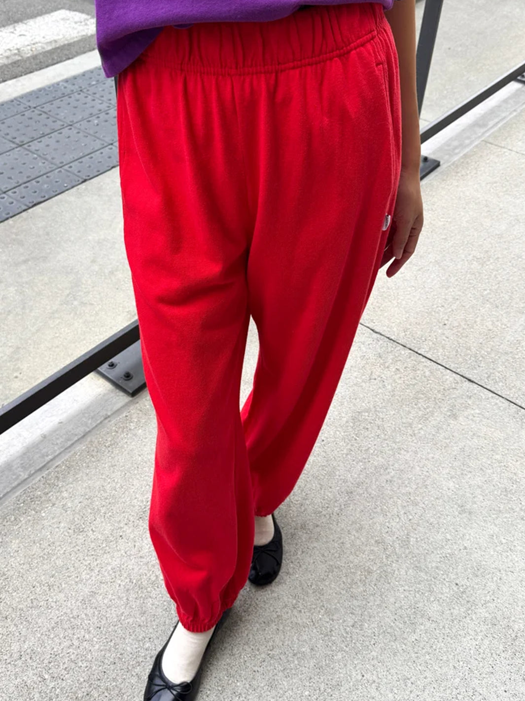 Front view of model wearing red balloon pants with an elastic waistband, side pockets and gathered cuffs | Twentyseven Toronto