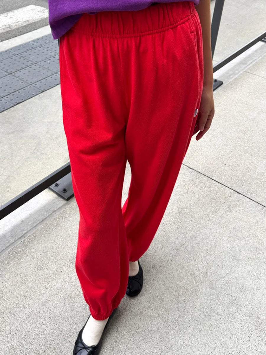 Front view of model wearing red balloon pants with an elastic waistband, side pockets and gathered cuffs | Twentyseven Toronto