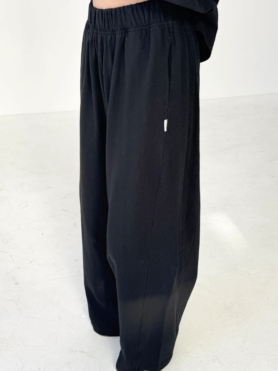 Person wearing wide-leg Bare Pants in 'Black' from Le Bon Shoppe and a white top on a white background, side view | Twentyseven Toronto