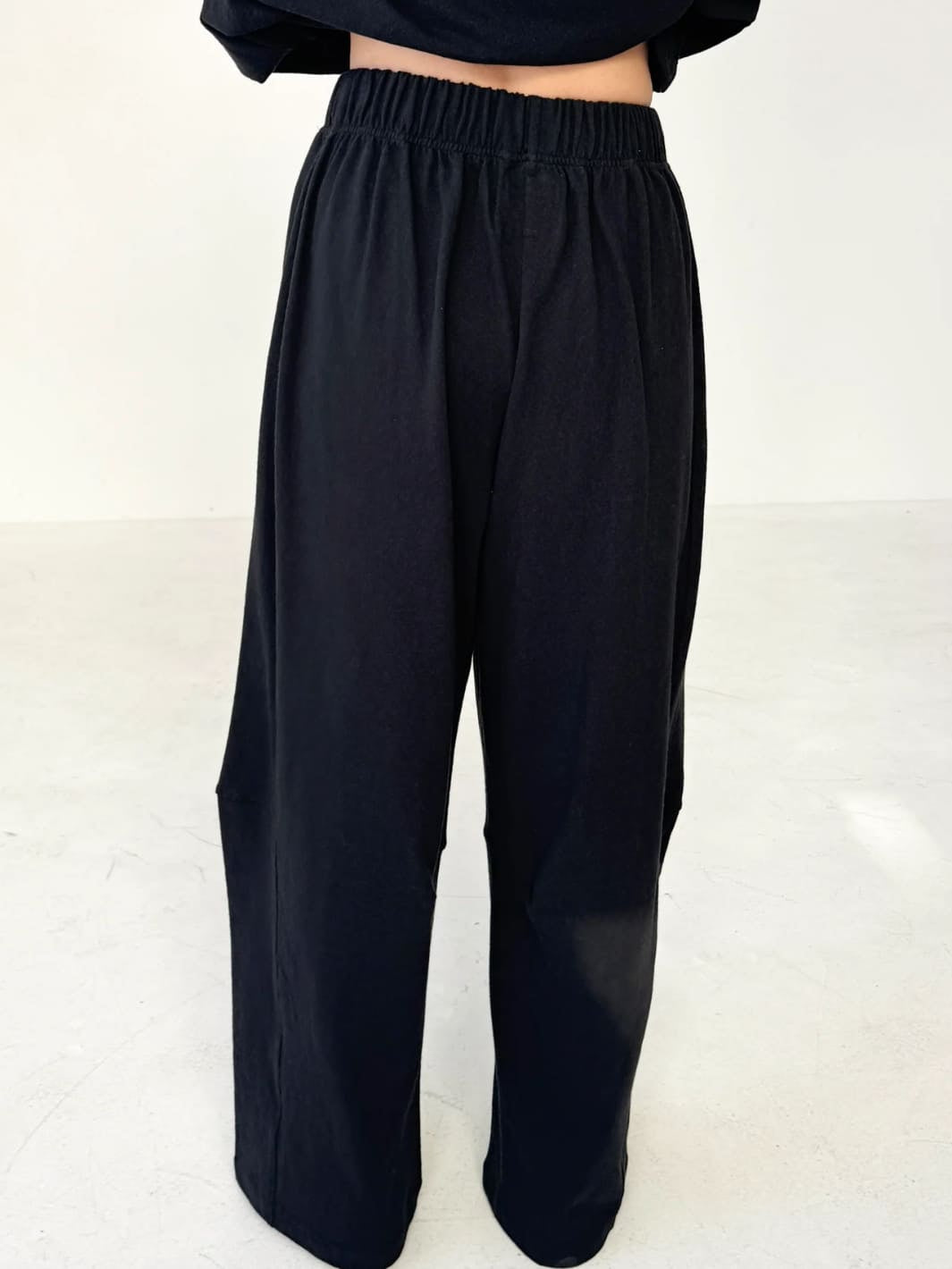 Person wearing wide-leg Bare Pants in 'Black' from Le Bon Shoppe and a white top on a white background, back view | Twentyseven Toronto
