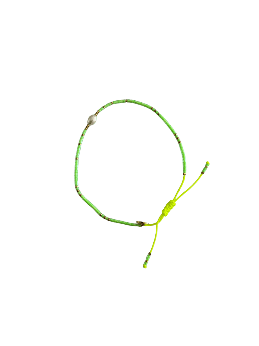 Bracelet with neon green cord, small gold and light green beads and single white pearl on a transparent background | Twentyseven Toronto