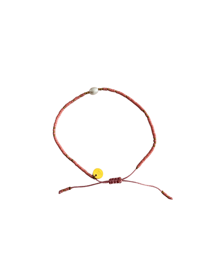 Bracelet with pink cord, small pink and gold beads and single white pearl on a transparent background | Twentyseven Toronto