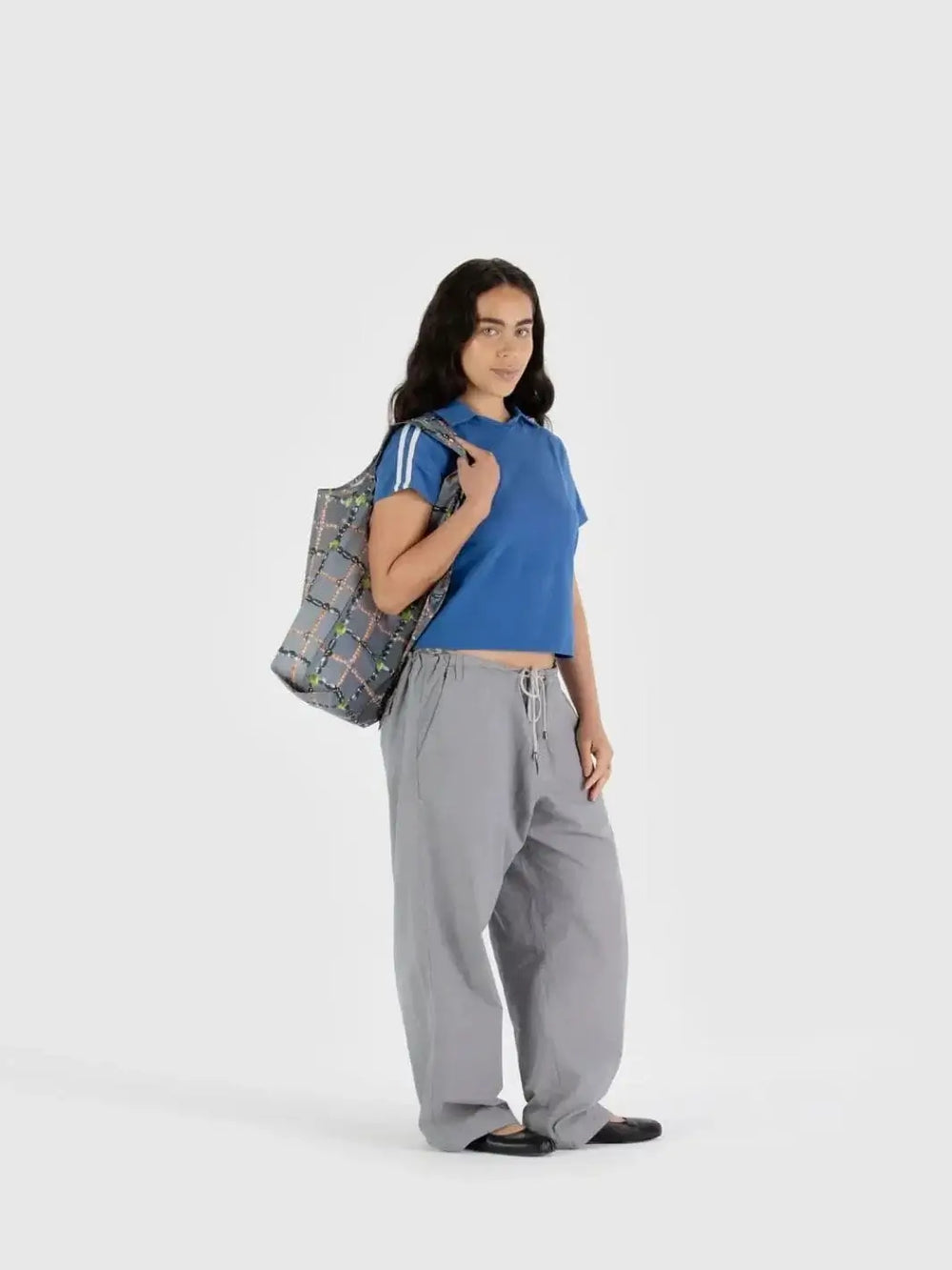 A person standing against a plain white backdrop carries the gray, pearl-patterned Baggu Beaded Plaid Bag over their shoulder | Twentyseven Toronto