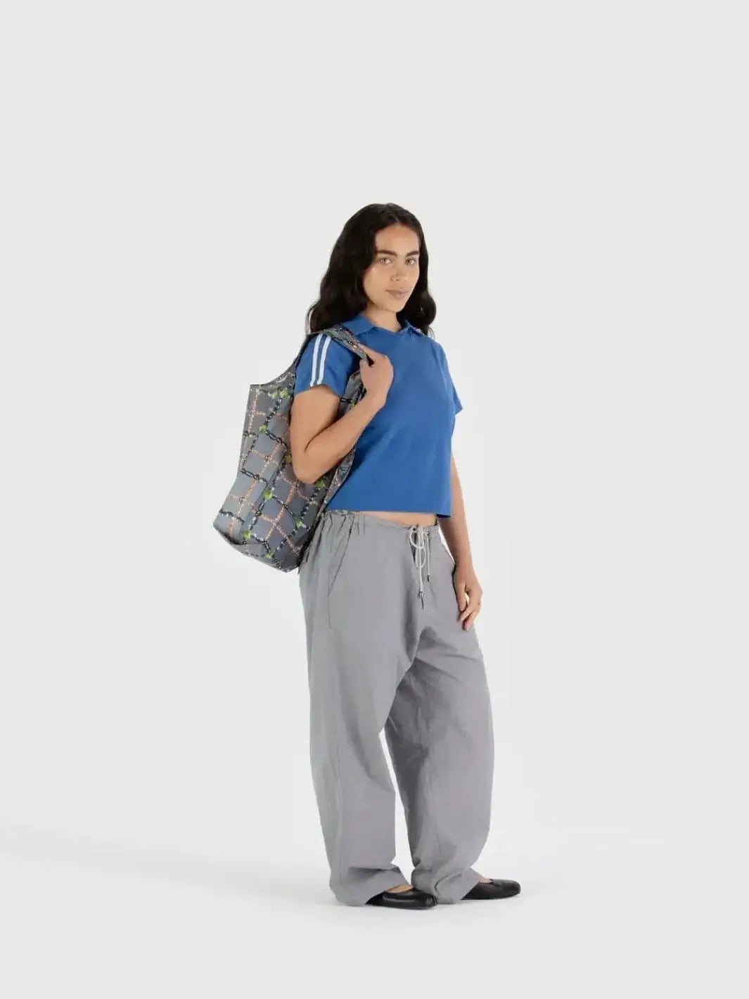 A person standing against a plain white backdrop carries the gray, pearl-patterned Baggu Beaded Plaid Bag over their shoulder | Twentyseven Toronto
