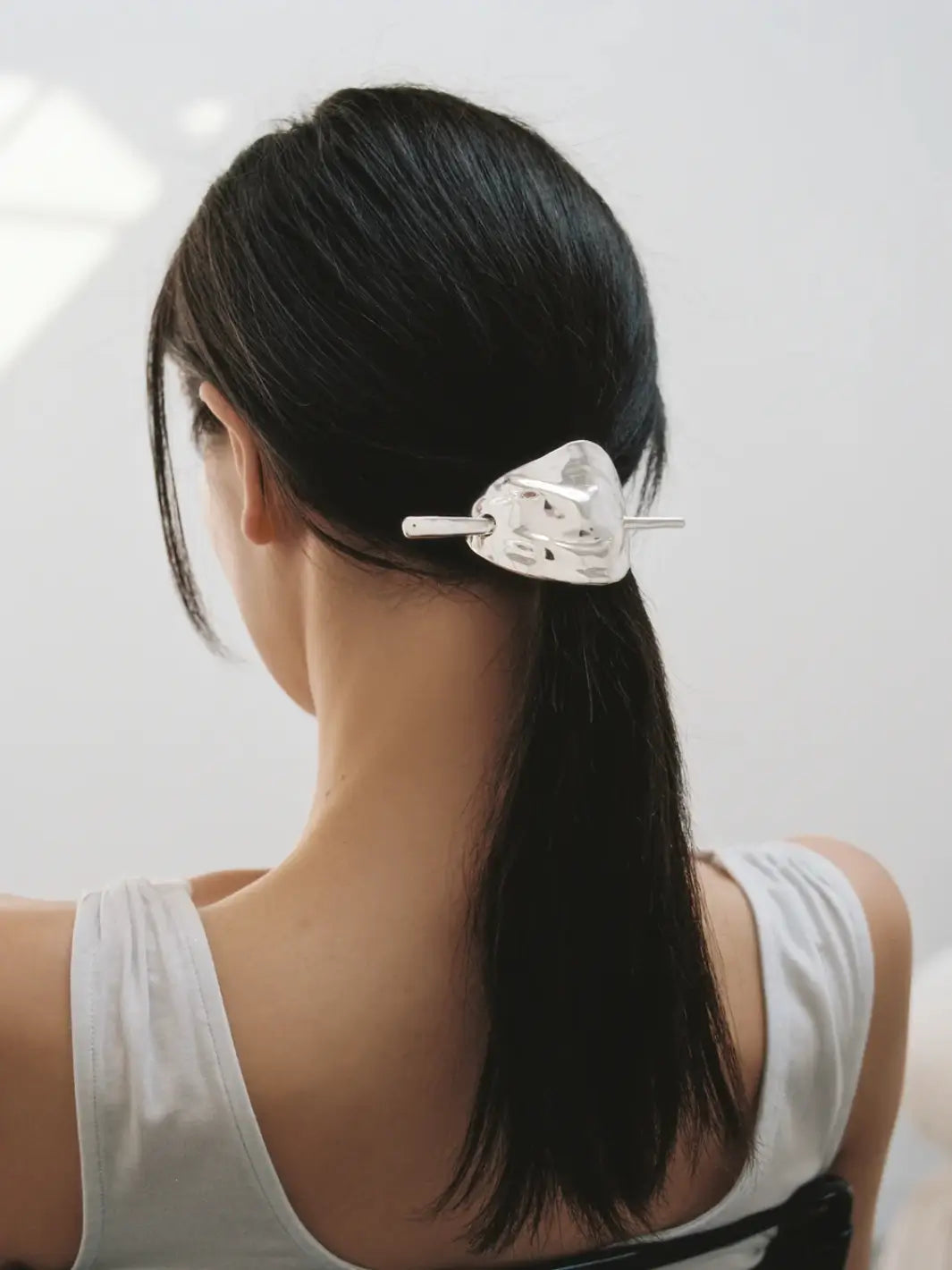 A woman wearing a reflective, silver hair clip called the Bean French Pin in Silver from Wolf Circus against a white background | Twentyseven Toronto