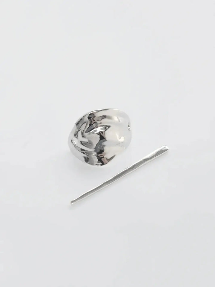 The two separate components of the Bean French Pin in Silver from Wolf Circus, including the curved metallic shield and the straight fastening stick on a white background | Twentyseven Toronto