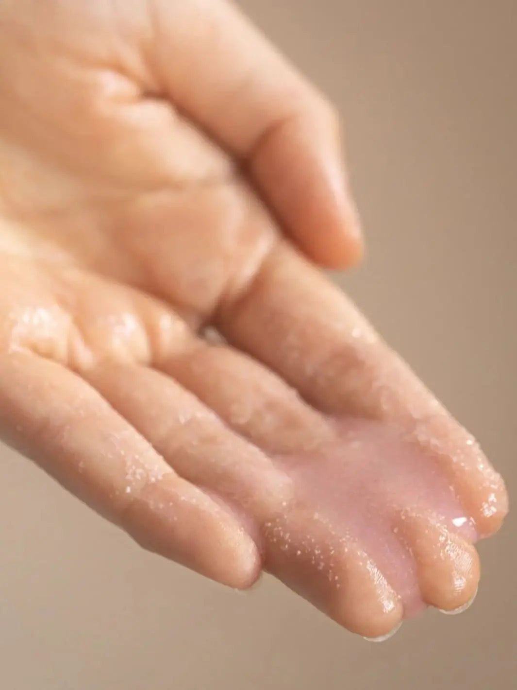 Beauty from Bees Shower Scrub | Twentyseven Toronto | Close-up of a hand with Beauty from Bees Shower Scrub liquid on a beige background