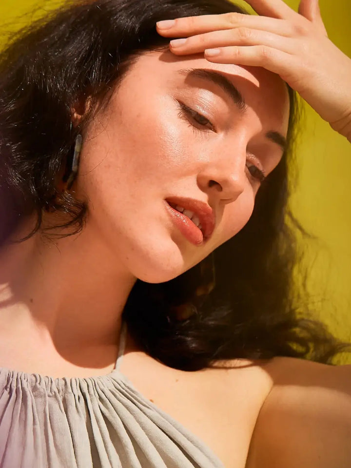 Woman using Olio E Osso Bel Corpo Body Oil on a yellow background | Twentyseven Toronto