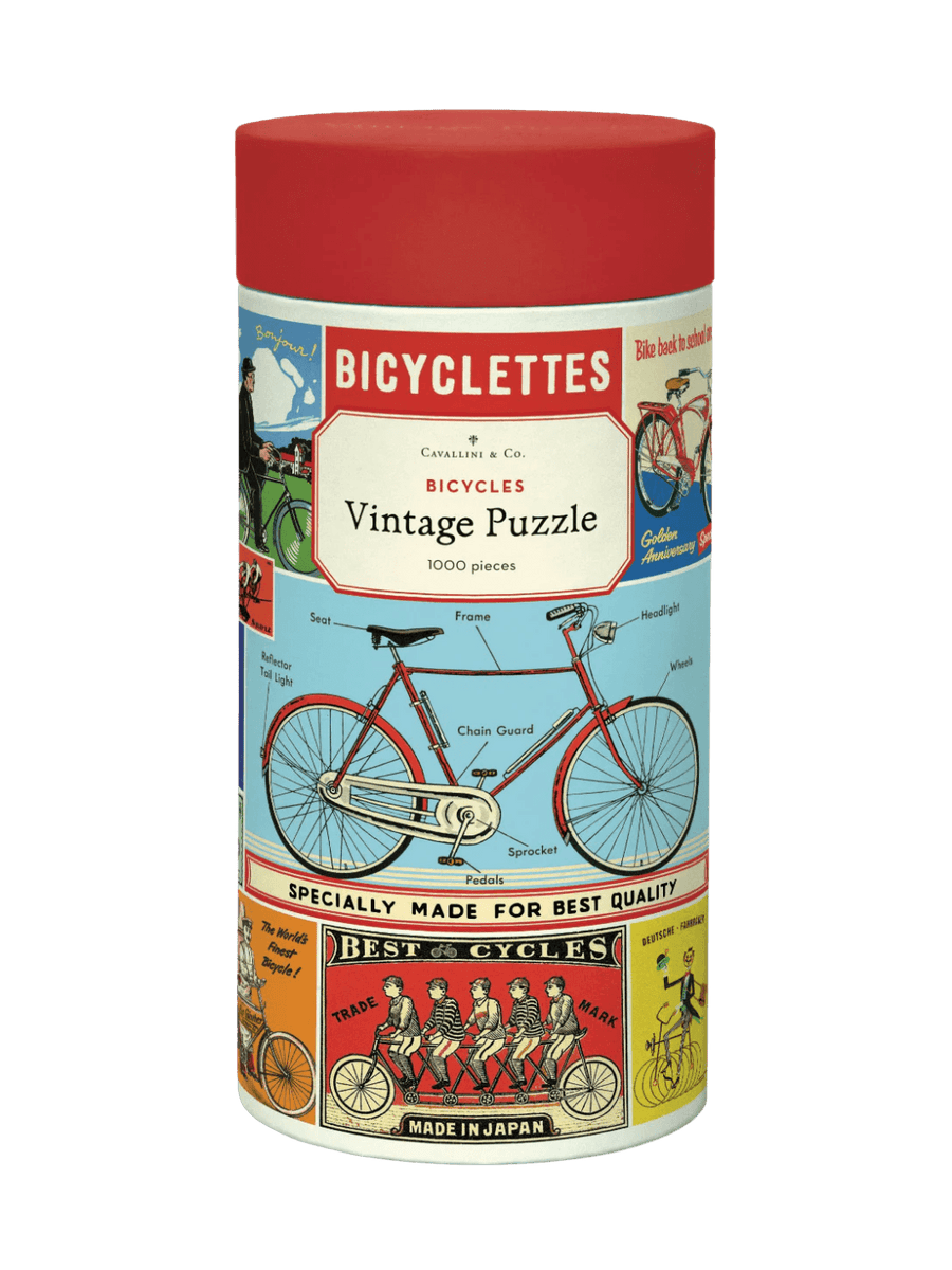 Cylindrical paper tube for the Cavallini Paper & Co Bicycles 1000 Piece Puzzle, highlighting a red diagram of a classic bicycle with labeled parts below its vintage title card | Twentyseven Toronto
