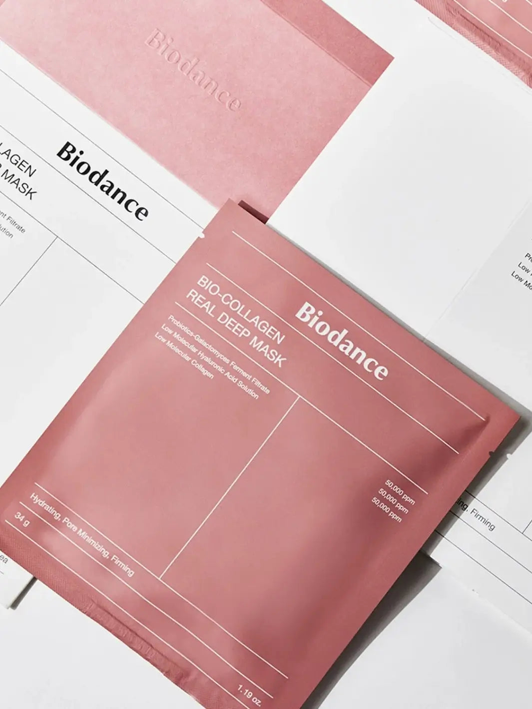 A square, dusty-pink product pouch for the Biodance Bio - Collagen Real Deep Mask lies flat on top of white and pink brand paperwork | Twentyseven Toronto