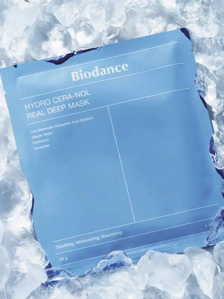 A blue package of the Biodance Hydro Cera-nol Real Deep Sheet Mask surrounded by and resting on a bed of crushed ice cubes to emphasize its cooling effect | Twentyseven Toronto