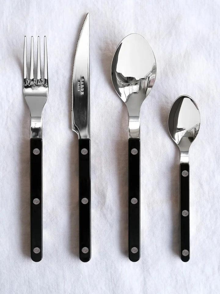 Four pieces from the Sabre Paris Bistrot Solid Shiny 5 Piece Cutlery Set in Black, including a soup spoon, a dinner fork, a dinner knife and a teaspoon | Twentyseven Toronto