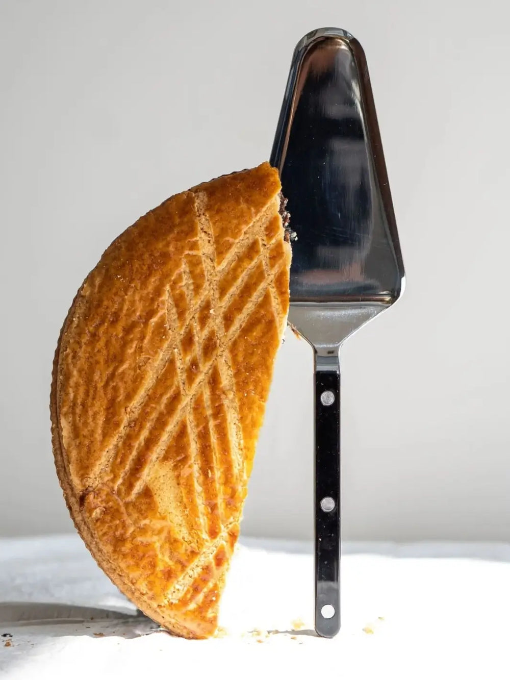 Sabre Paris Bistrot Solid Shiny Tart Server in Black stands upright beside a sliced golden-brown tart | Twentyseven Toronto
