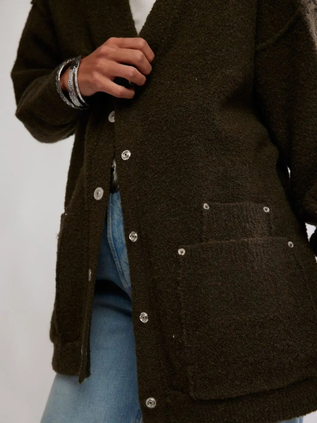 A close-up shot highlights the textured, bouclé knit material, snap-button closure, and front patch pockets of the Free People Blazing Cardi in Dark Green | Twentyseven Toronto