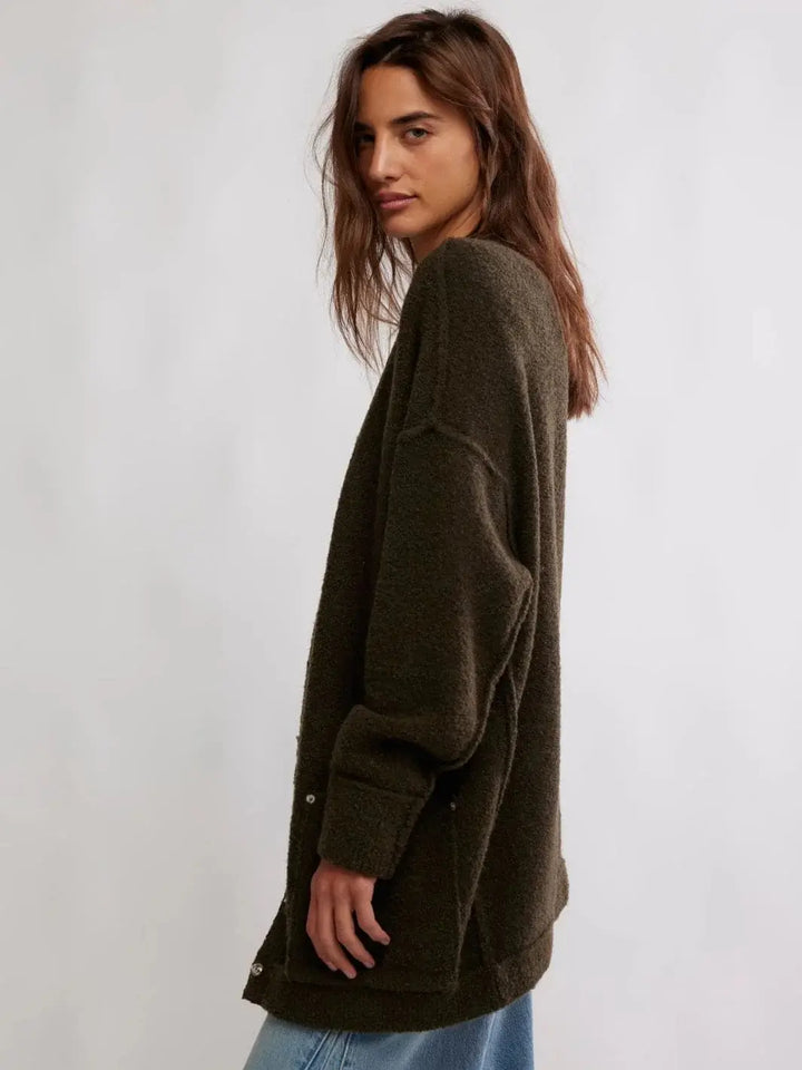 A side profile view displays the relaxed, comfortable drape and elongated hem of the Free People Blazing Cardi in Dark Green | Twentyseven Toronto