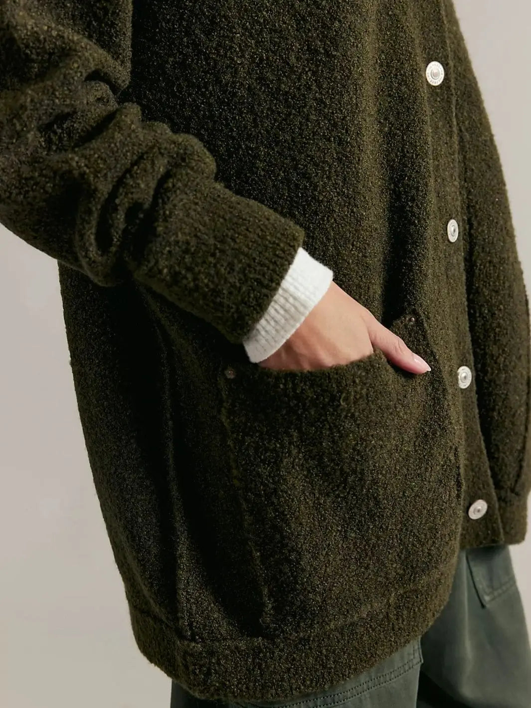 A detailed close-up shot focuses on a hand resting inside the deep front patch pocket of the textured Free People Blazing Cardi in Dark Green | Twentyseven Toronto