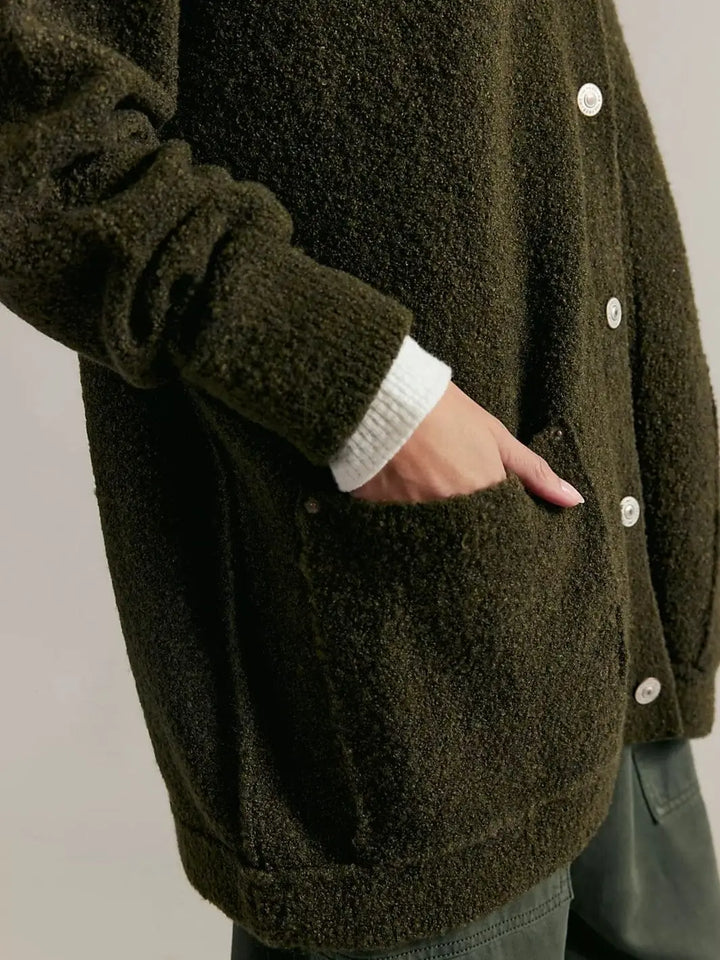 A detailed close-up shot focuses on a hand resting inside the deep front patch pocket of the textured Free People Blazing Cardi in Dark Green | Twentyseven Toronto