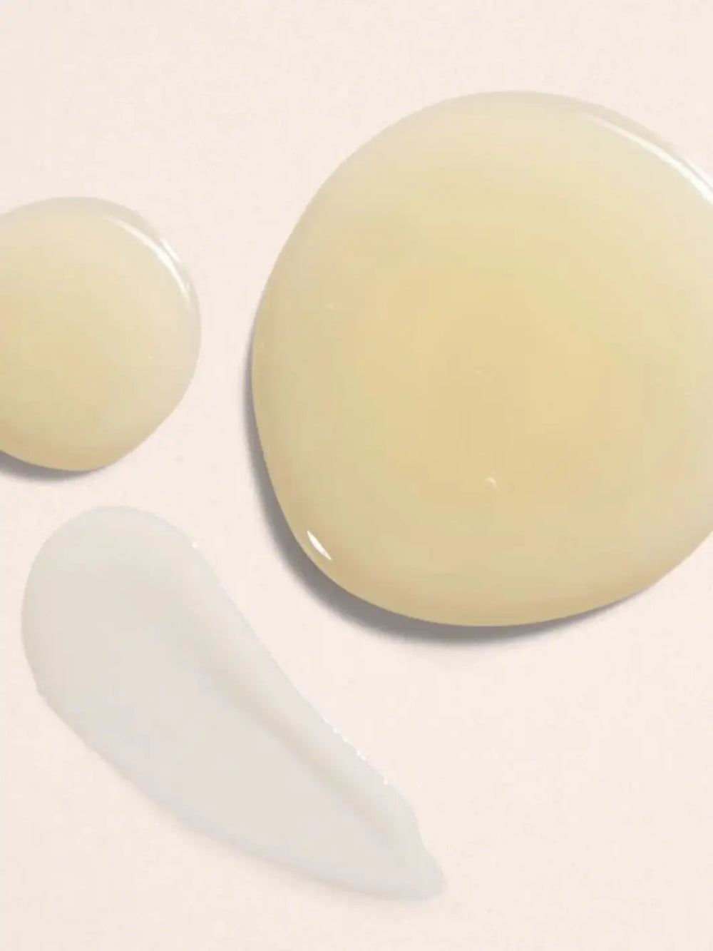 Two round, light-coloured body serum product drops by Beauty from Bees on a beige background | Twentyseven Toronto