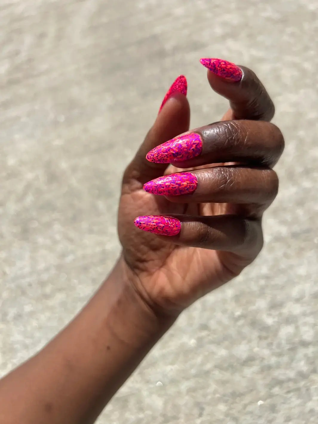 A hand with a deep skin tone captures the multi-dimensional pink shade, textured glitter finish of Death Valley Nails Bone Daddy Nail Polish | Twentyseven Toronto