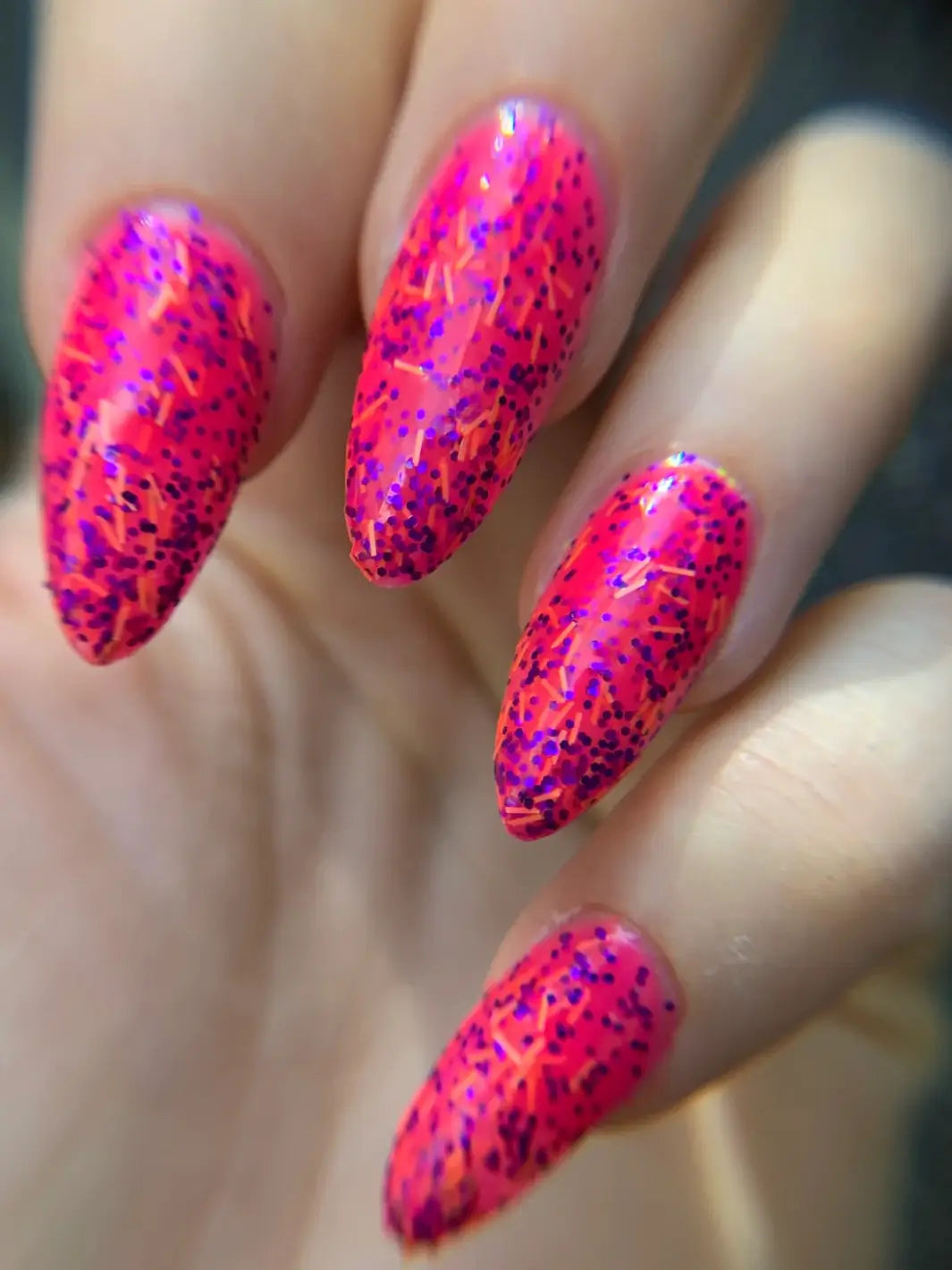 A close-up of a full manicure of long, stiletto nails coated in Death Valley Nails Bone Daddy Nail Polish, emphasizing the dense distribution of purple and orange glitters | Twentyseven Toronto
