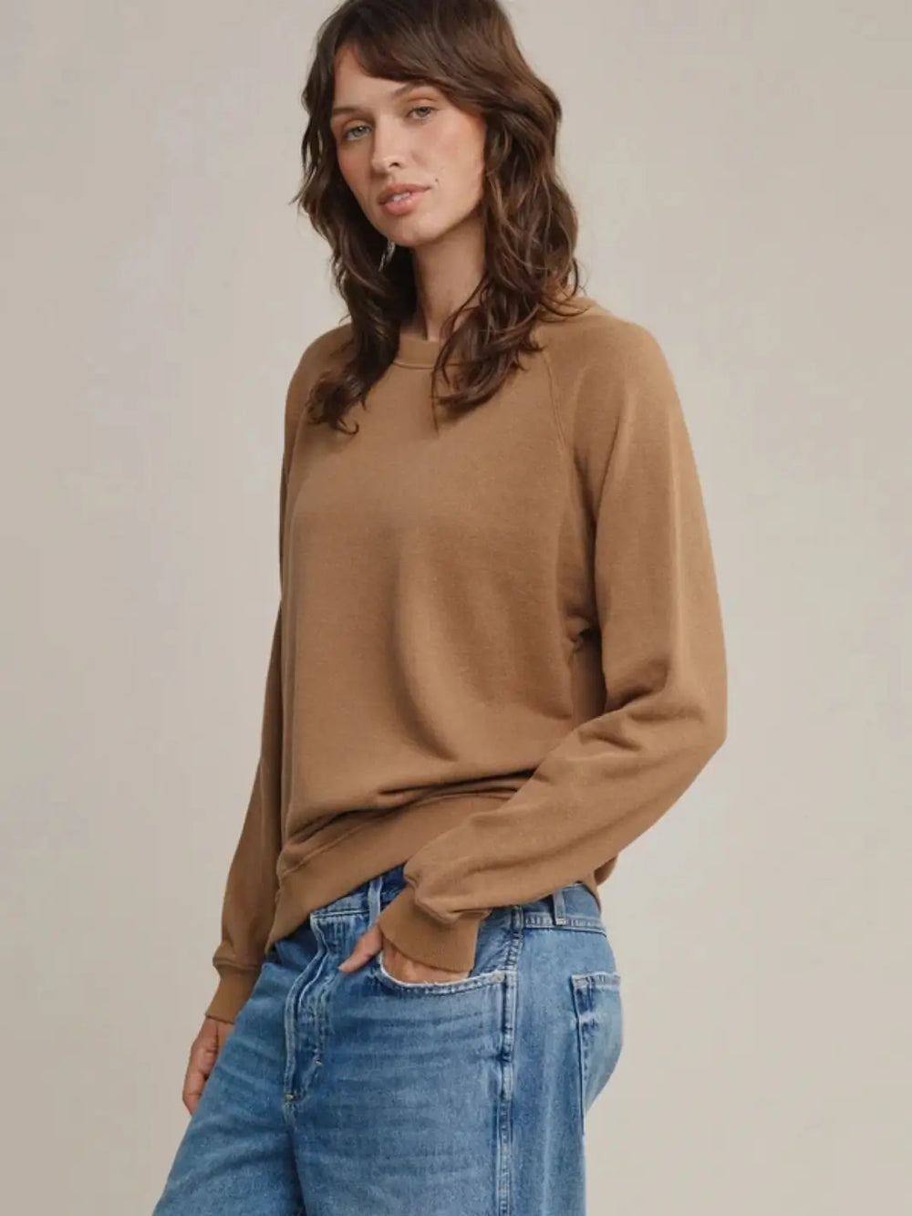 Front three-quarter view of a brunette woman wearing the brown Jungmaven Bonfire Raglan Sweatshirt with blue jeans | Twentyseven