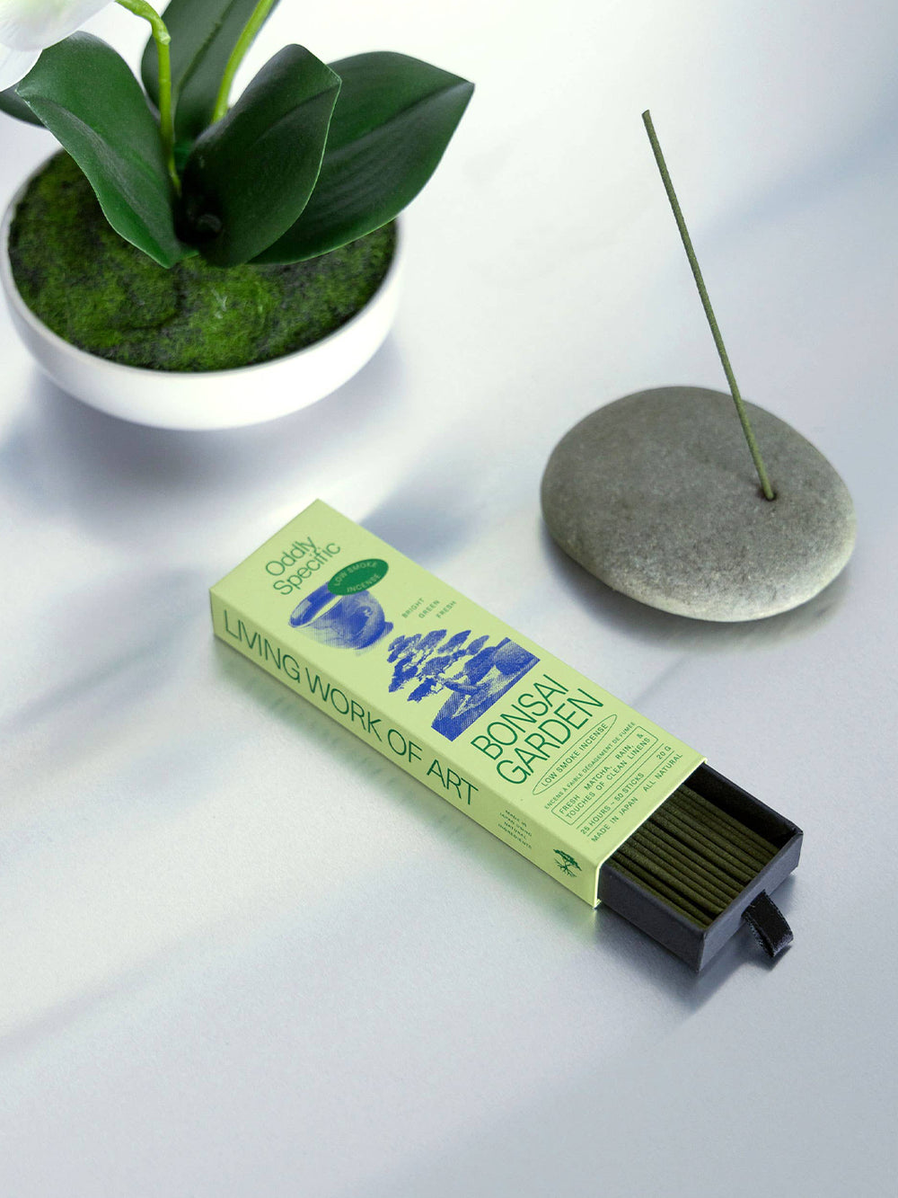 Oddly Specific Bonsai Garden Low Smoke Incense in green packaging with an open drawer of incense sticks, styled beside a burning incense holder and potted greenery | Twentyseven Toronto