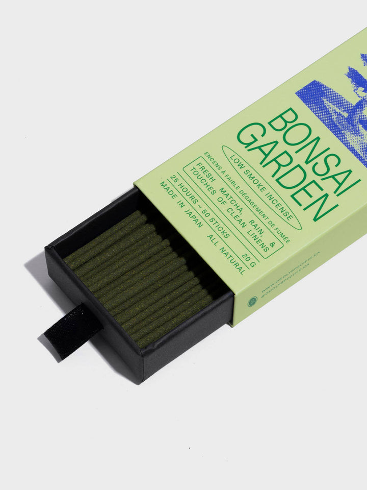 Close-up of Oddly Specific Bonsai Garden Japanese incense featuring olive green sticks in a black pull-out tray and light green packaging with blue bonsai artwork | Twentyseven Toronto