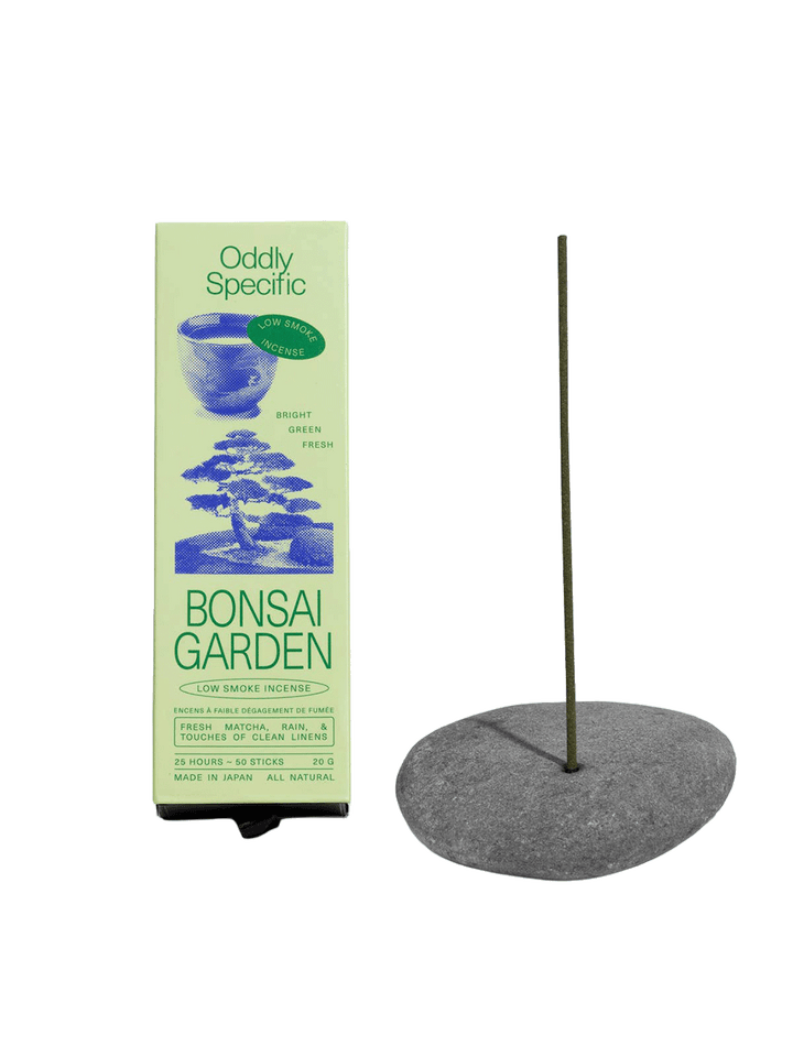 Oddly Specific Bonsai Garden Low Smoke Incense in light green packaging with blue Japanese garden illustrations, displayed beside a green incense stick in a grey stone holder | Twentyseven Toronto