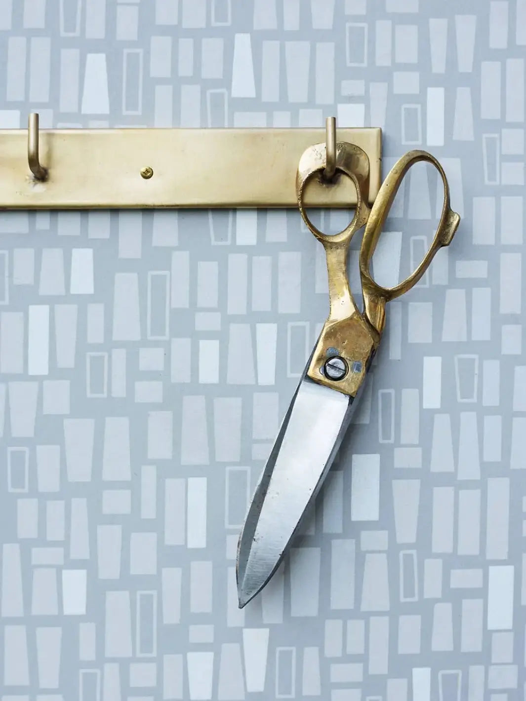 The Brass Handle Scissors Large from Fog Linen Work are shown in use, cutting through a piece of neutral-toned fabric | Twentyseven Toronto